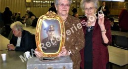 Sisters of Cpl. Arnold B. Stavinoha pose with his portrait and a toolbox he made while home on leave. Viola (in red jacket) holds his recovered ID bracelet in her left hand.